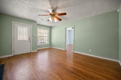 a view of an empty room with wooden floor and a window