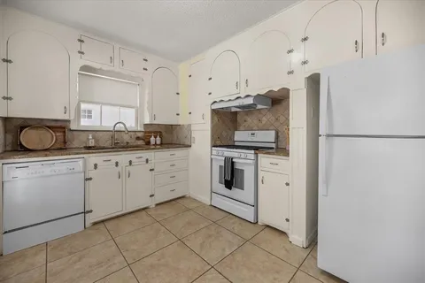 a kitchen with white cabinets and white appliances