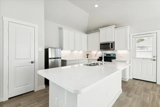 a kitchen with kitchen island a white counter top space cabinets and stainless steel appliances