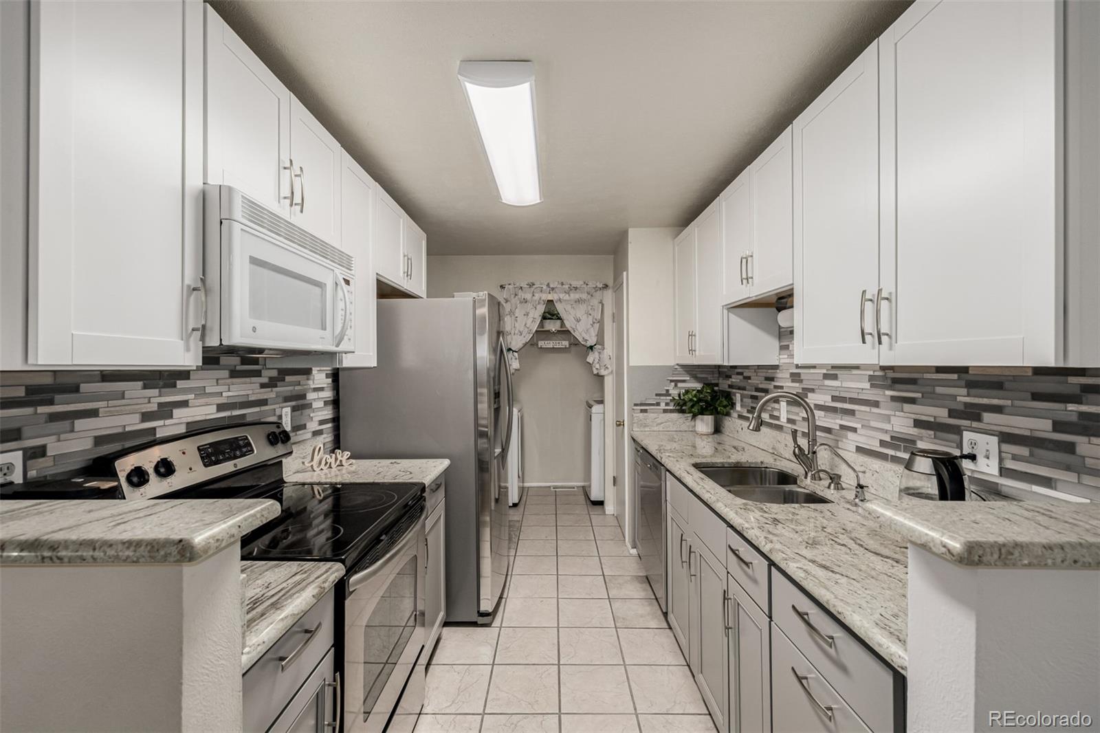 7624 Gray Way Arvada, CO 80003 - Photo 14 of 39 a kitchen with stainless steel appliances granite countertop a sink stove and refrigerator