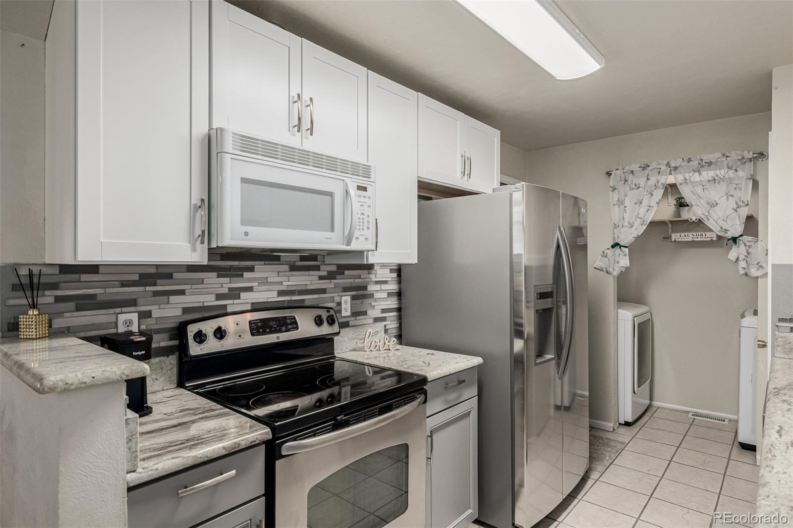 7624 Gray Way Arvada, CO 80003 - Photo 16 of 39 a kitchen with stainless steel appliances a stove a refrigerator and cabinets