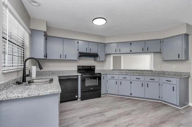 a kitchen with granite countertop a sink stove and cabinets