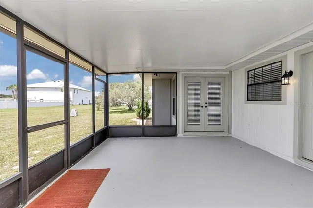 a view of an empty room with a window and a kitchen