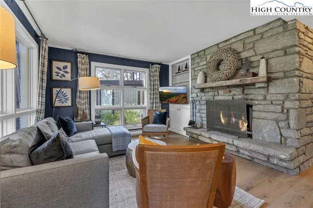 a living room with furniture a fireplace and a floor to ceiling window