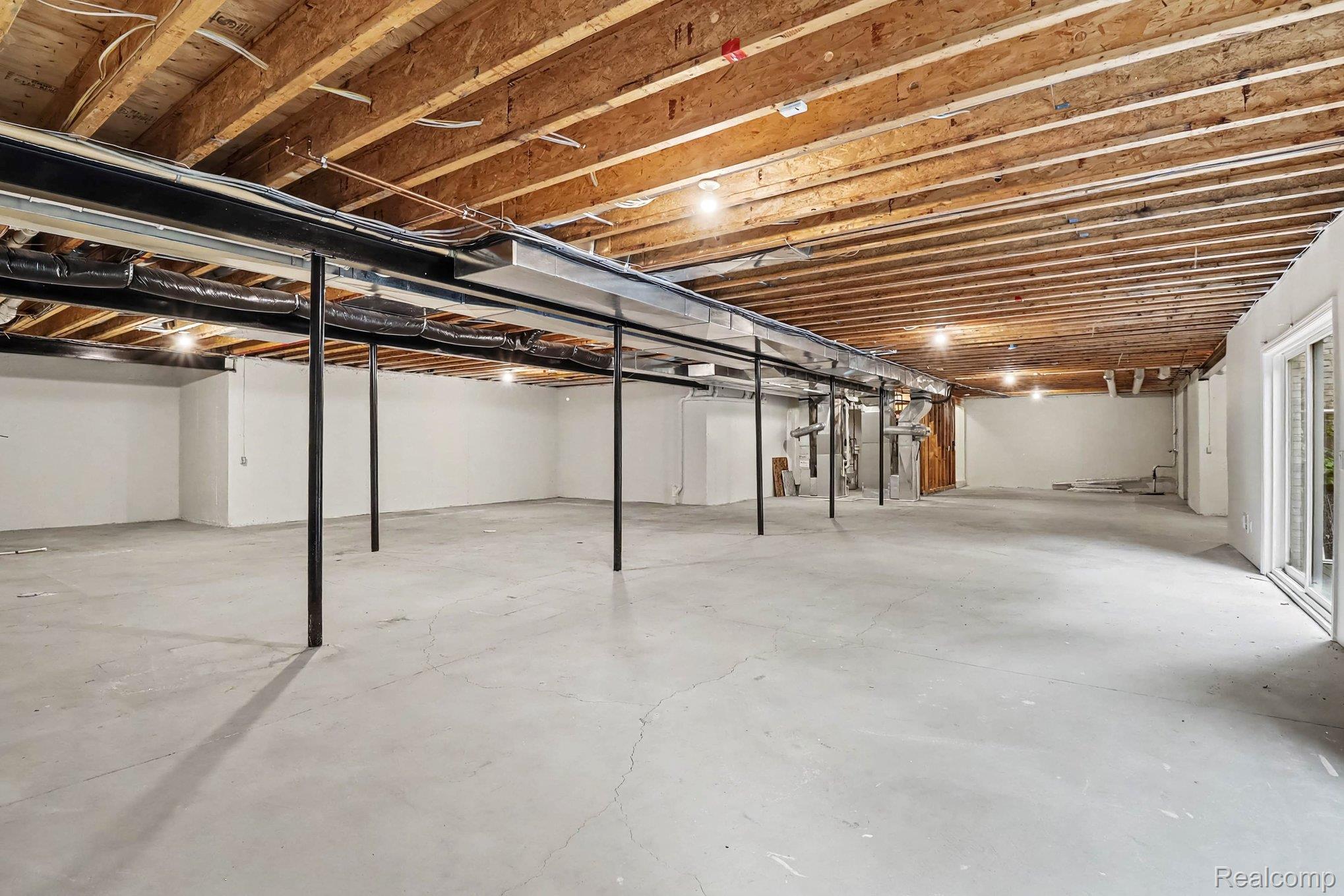 4875 Green Meadow Lane Rochester, MI 48306 - Photo 44 of 60 Expansive unfinished basement featuring exposed wood joists, concrete flooring, recessed lighting, and a sliding glass door