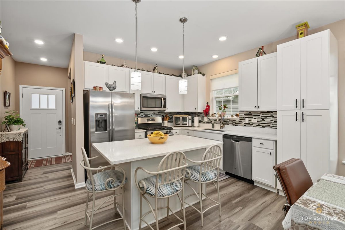 2010 Azure Lane Algonquin, IL 60102 - Photo 12 of 41 a kitchen with stainless steel appliances kitchen island granite countertop a refrigerator a stove a sink a dining table and chairs with wooden floor