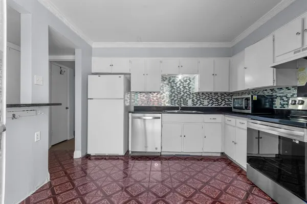 a kitchen with white cabinets and refrigerator