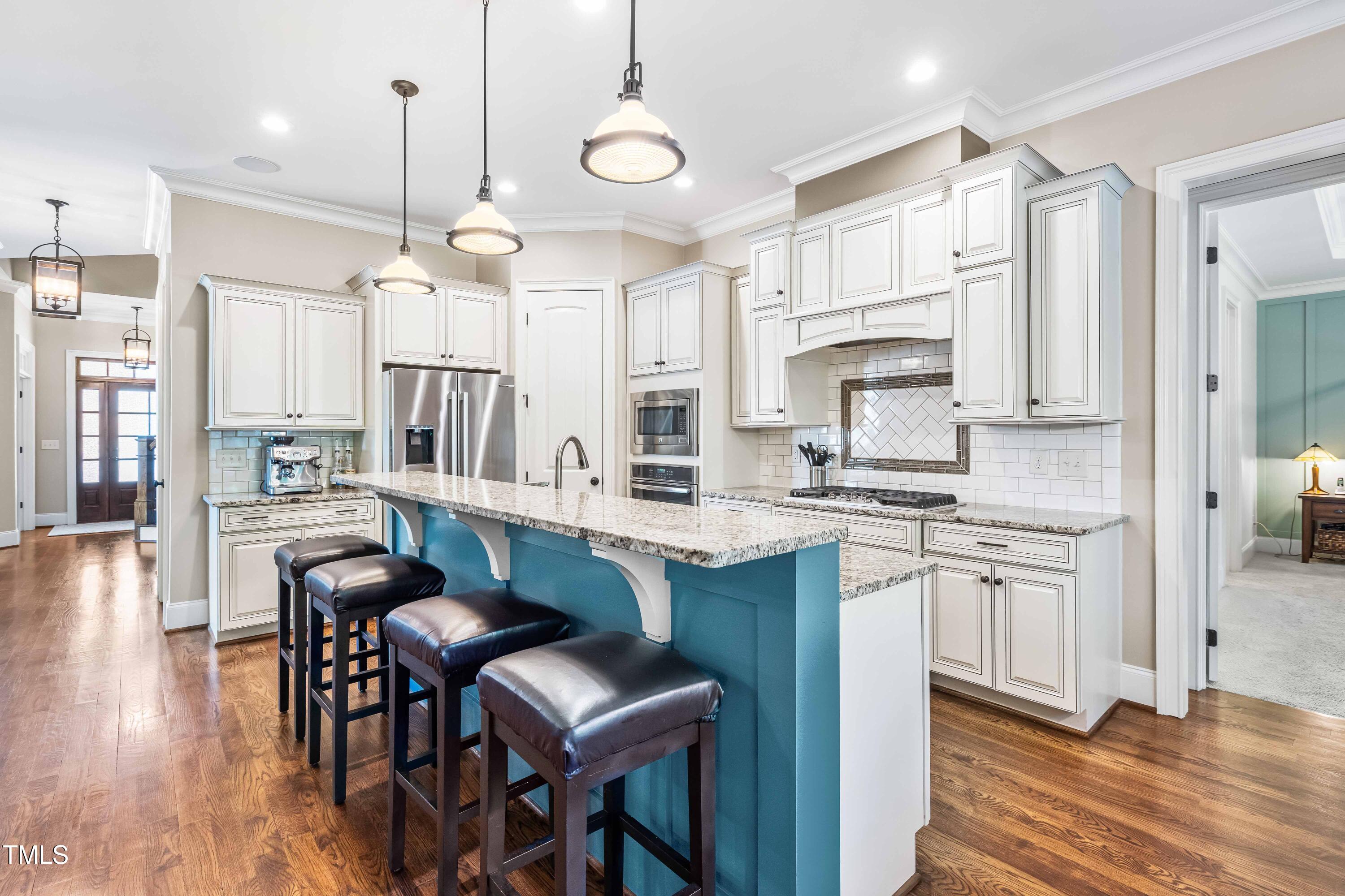 2538 Tuffeto Apex, NC 27502 - Photo 12 of 55 a kitchen with stainless steel appliances granite countertop a stove a sink a refrigerator and a dining table with wooden floor