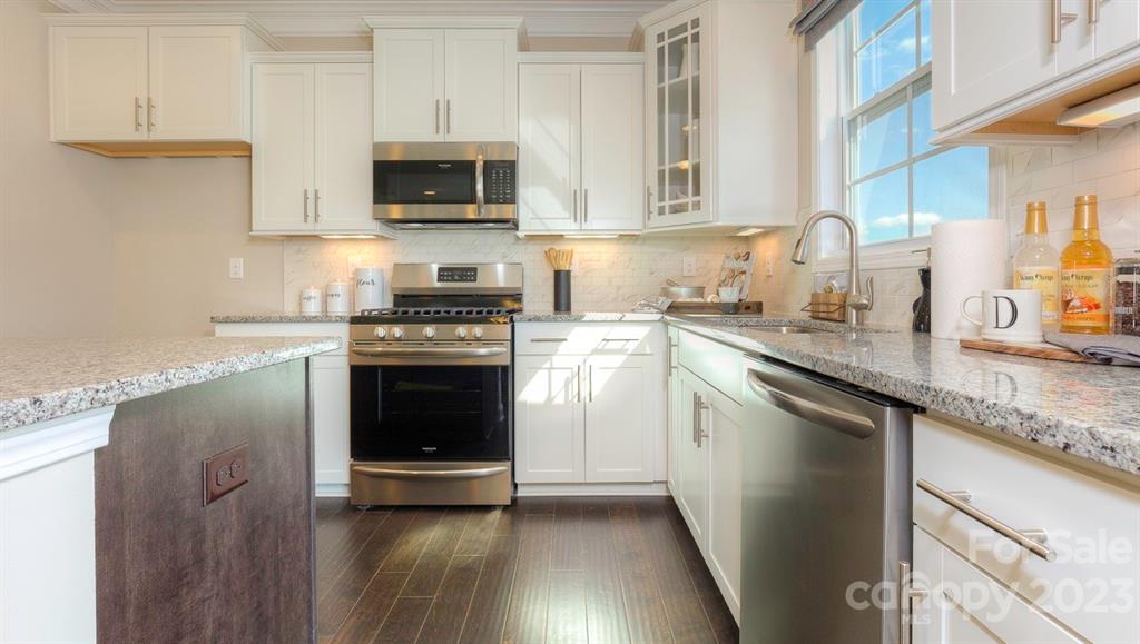 679 Fox Cove Road Hendersonville, NC 28792 - Photo 9 of 35 a kitchen with granite countertop a stove top oven a sink and dishwasher with wooden floor