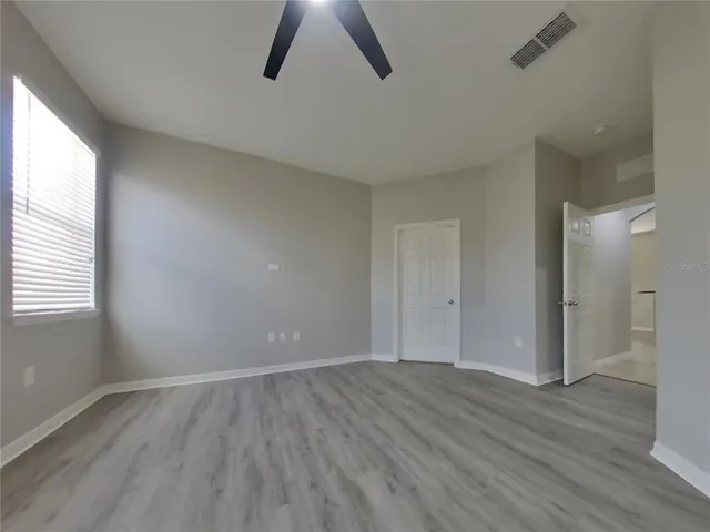 an empty room with wooden floor and windows