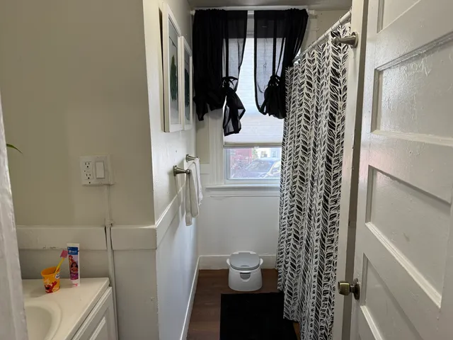 a bathroom with a shower curtain a window and a shower
