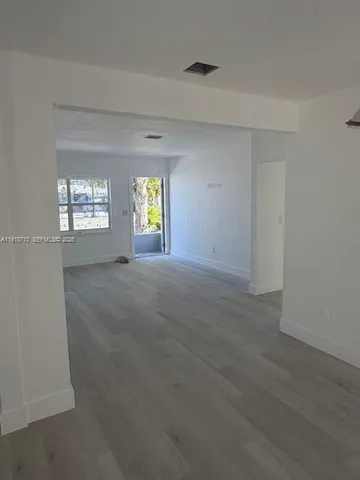 a view of a kitchen with white cabinets and wooden floor