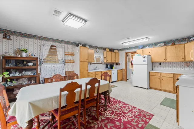 a open kitchen with stainless steel appliances granite countertop a stove a refrigerator a dining table and chairs with wooden floor