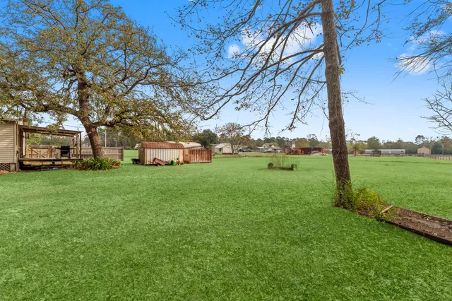 a yellow and red house with a big yard and large trees