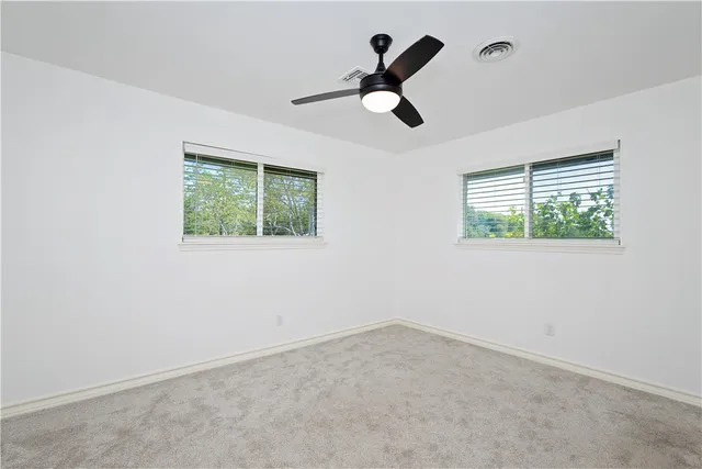 an empty room with a window and a fan