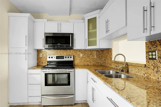 a kitchen with granite countertop white cabinets a sink and a stove oven with wooden floor