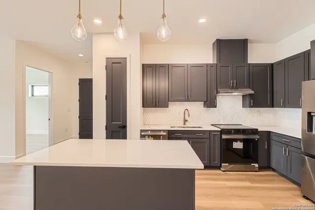 a kitchen with kitchen island granite countertop a sink a stove and refrigerator