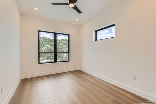 an empty room with wooden floor and windows