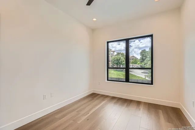 an empty room with wooden floor and windows