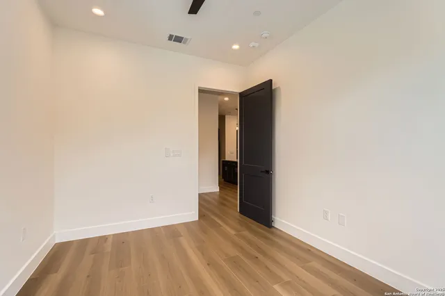 a view of an empty room with wooden floor and closet