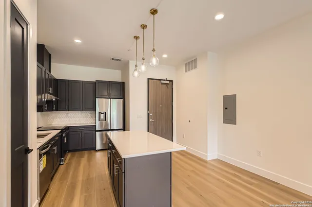 a kitchen with kitchen island a counter top space appliances and a ceiling fan
