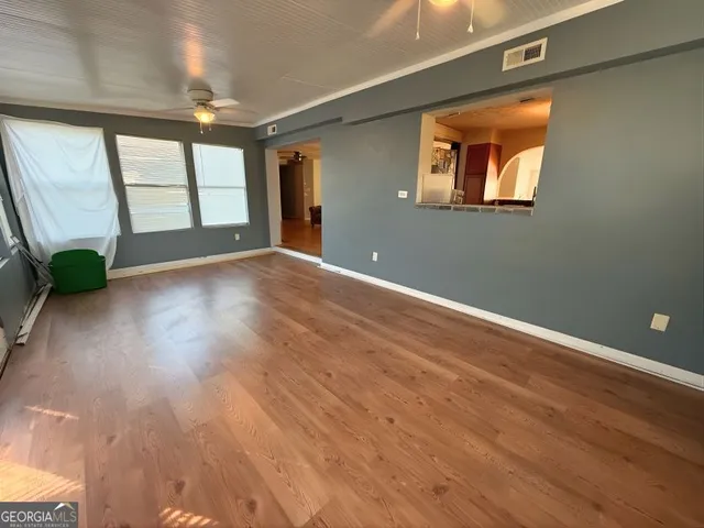 an empty room with wooden floor and windows
