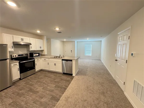 a kitchen with stainless steel appliances granite countertop a refrigerator a sink a stove a microwave a counter space and cabinets
