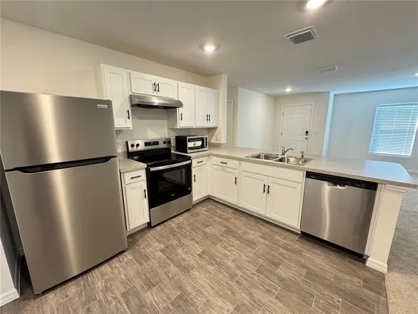 a large kitchen with kitchen island a stove a sink a refrigerator and black cabinets next to a window