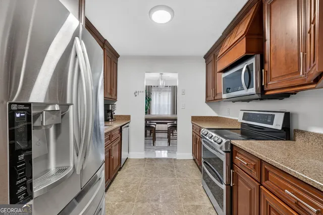a kitchen with stainless steel appliances granite countertop a refrigerator a stove and a sink