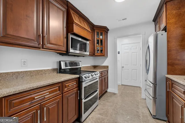a kitchen with stainless steel appliances granite countertop a refrigerator and a stove top oven