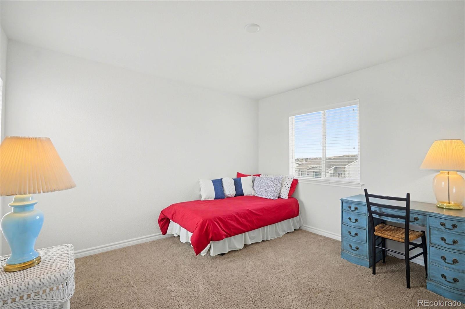 10844 Huntwick Street Highlands Ranch, CO 80130 - Photo 18 of 29 a bedroom with a bed and a lamp on dresser