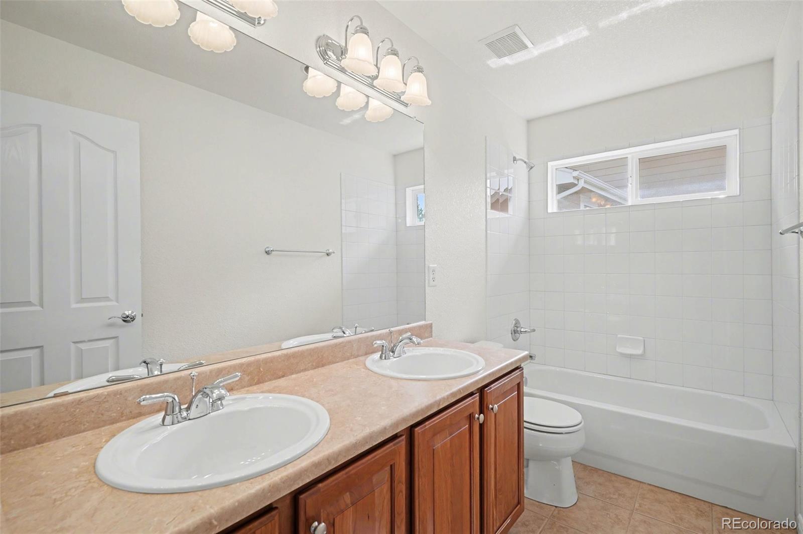 10844 Huntwick Street Highlands Ranch, CO 80130 - Photo 19 of 29 a bathroom with a granite countertop sink a toilet a mirror and shower