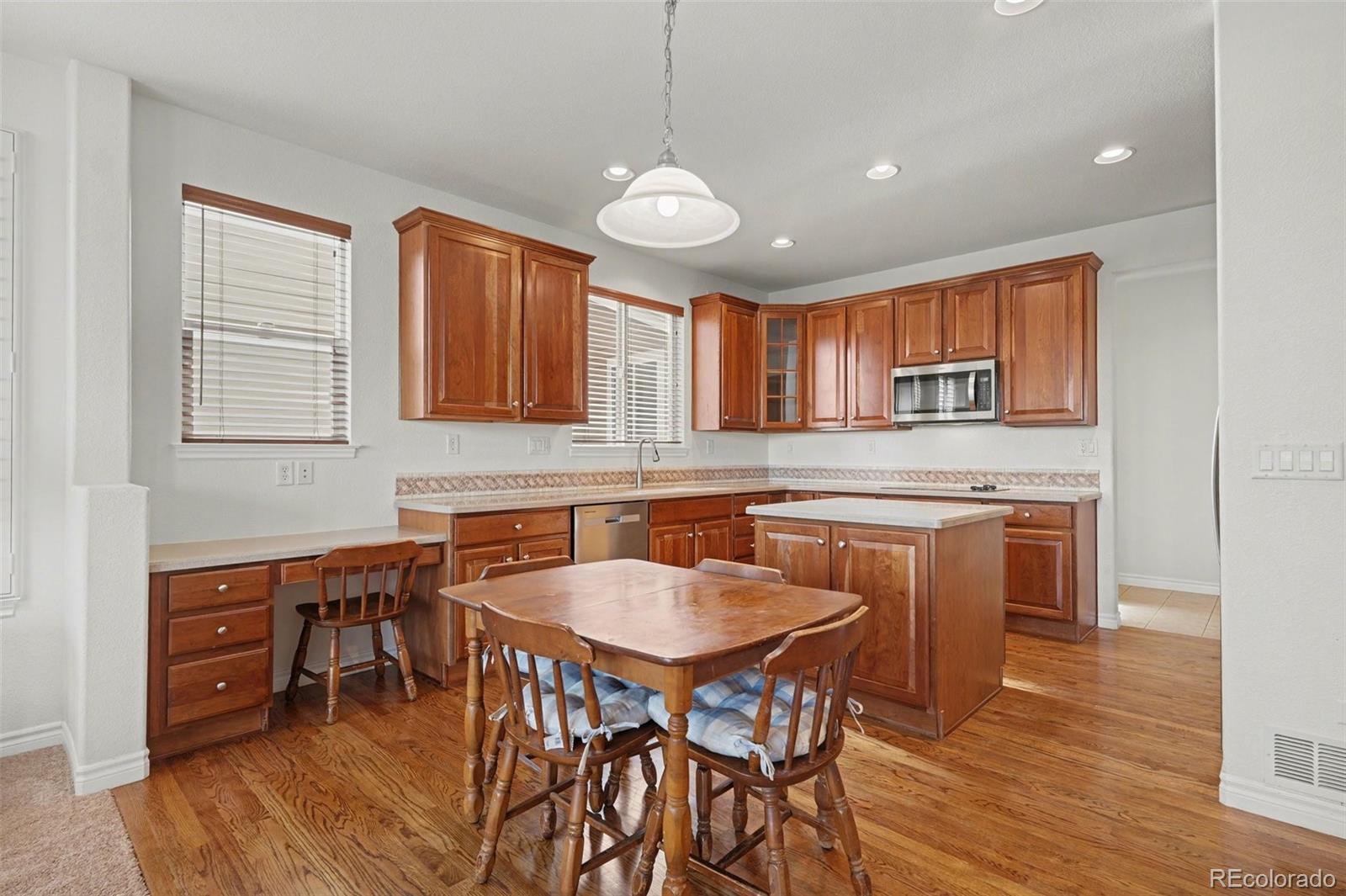 10844 Huntwick Street Highlands Ranch, CO 80130 - Photo 5 of 29 a kitchen with stainless steel appliances granite countertop a stove a sink a oven a dining table and chairs with wooden floor