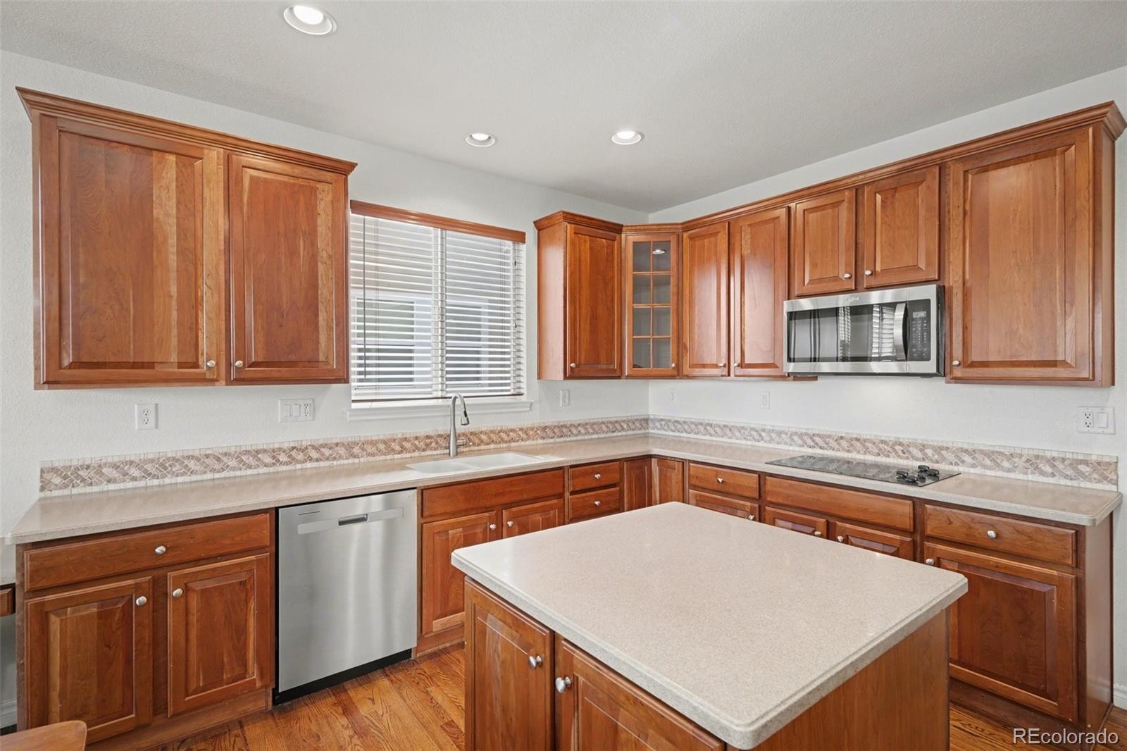 10844 Huntwick Street Highlands Ranch, CO 80130 - Photo 6 of 29 a kitchen with stainless steel appliances granite countertop a sink and cabinets with wooden floors