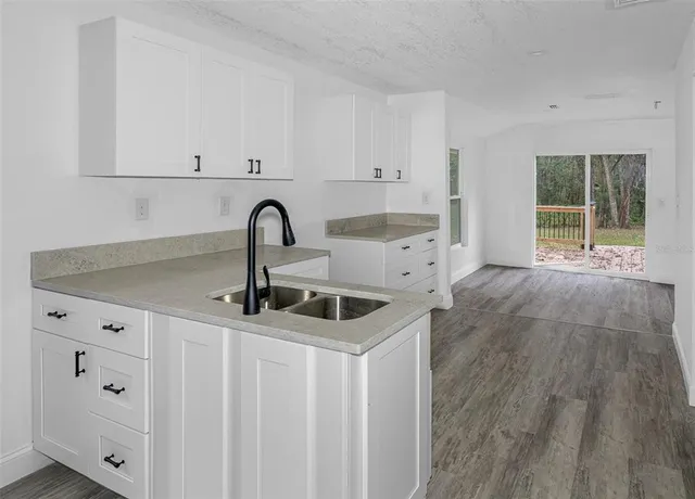 a kitchen with stainless steel appliances a sink a stove and white cabinets with wooden floor