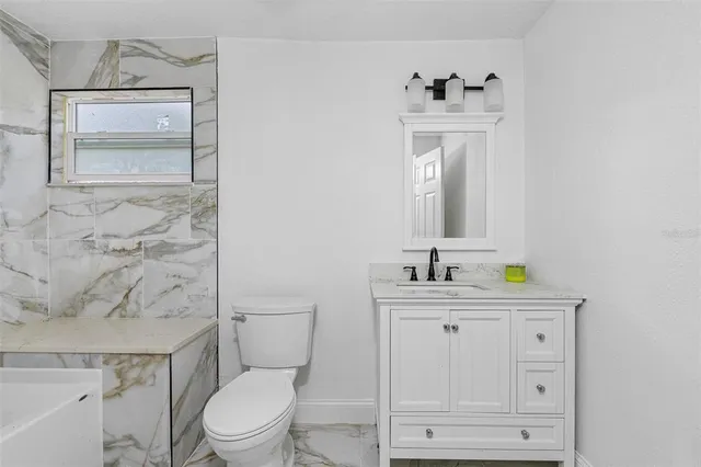 a bathroom with a granite countertop toilet sink and mirror