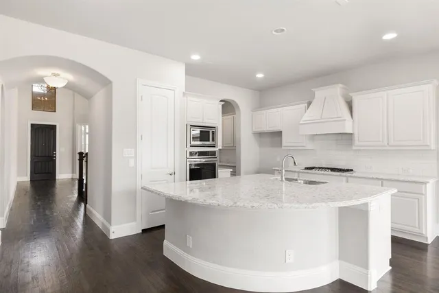 a view of a kitchen with stainless steel appliances granite countertop a stove a kitchen island a refrigerator and a sink