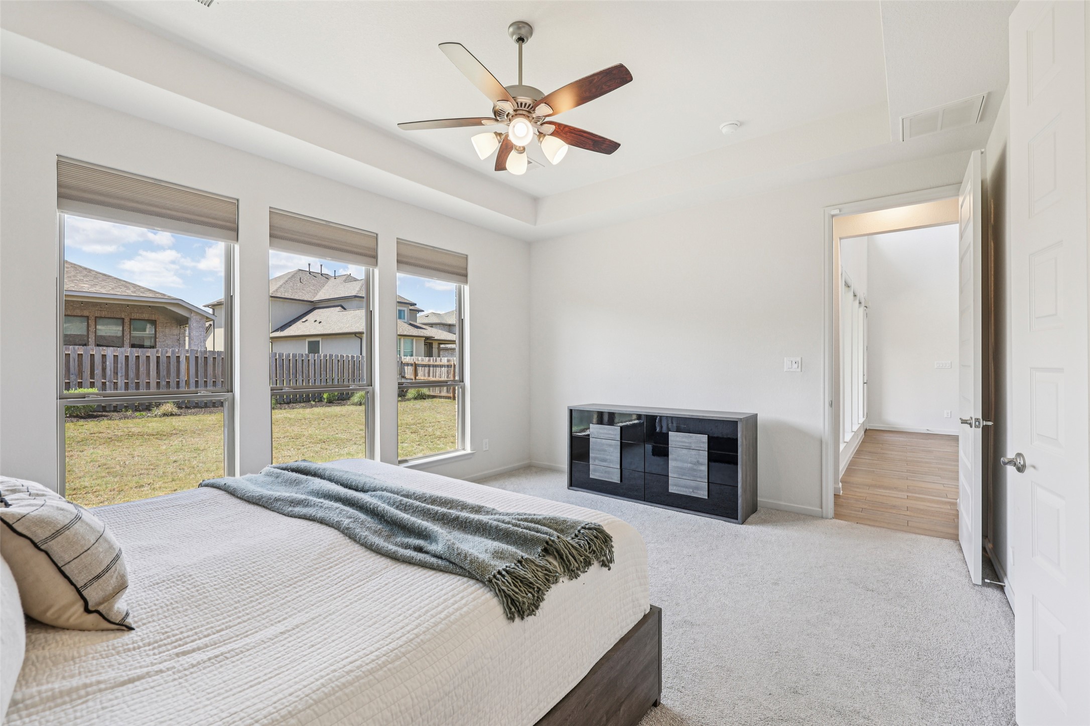 1140 Bryson Rdg Trail Leander, TX 78641 - Photo 15 of 39 This bedroom features a ceiling fan with integrated lighting, three large windows with window coverings, and light-colored carpeting