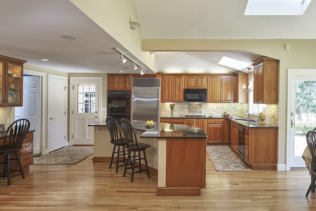 65 Montvale Road Weston, MA 02493 - Photo 4 of 11 a kitchen with stainless steel appliances kitchen island granite countertop a table chairs refrigerator and a sink