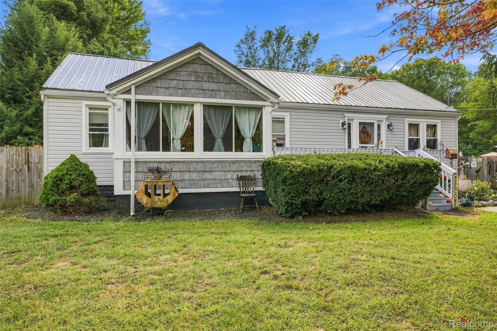 36739 Wick Road Romulus, MI 48174 - Photo 1 of 56 Siding exterior with a corrugated metal roof, front porch with white railing, and decorative front door