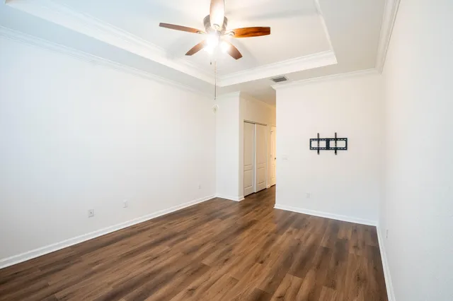 an empty room with wooden floor ceiling fan