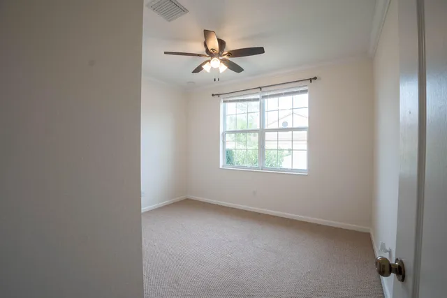 an empty room with ceiling fan and windows
