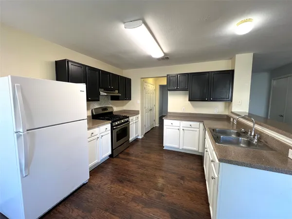 a kitchen with a refrigerator a microwave a sink and cabinets