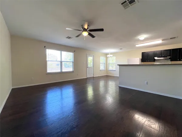an empty room with wooden floor and windows