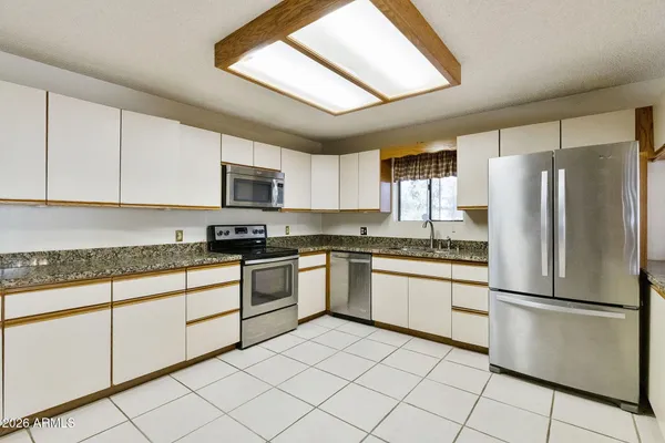 a kitchen with granite countertop a refrigerator and a stove top oven