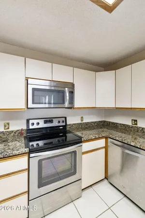a white kitchen with granite countertop stainless steel appliances