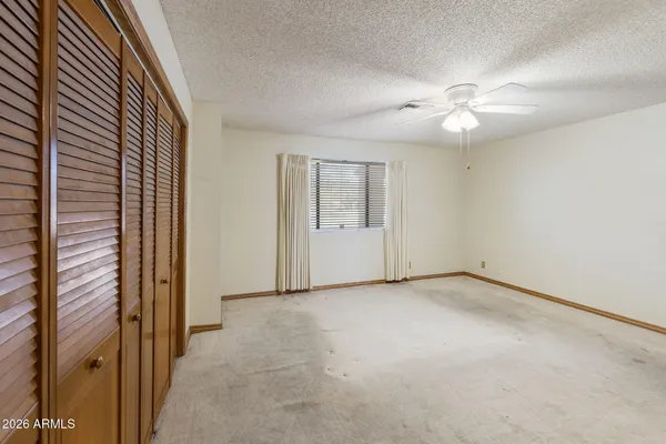 en empty room with windows and ceiling fan