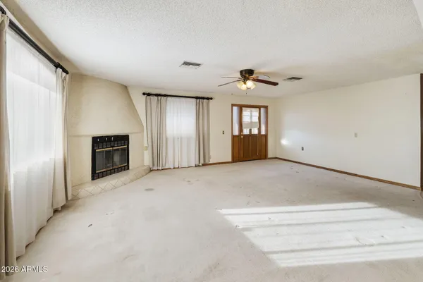 an empty room with windows and ceiling fan