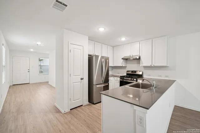 a kitchen with kitchen island granite countertop a sink and refrigerator