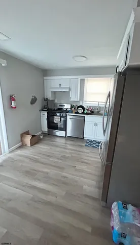 a kitchen with stainless steel appliances wooden floor and a refrigerator